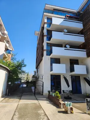 a white apartment building with a bench in front of it at Apart VILLA ITTA Sunny Beach in Sunny Beach