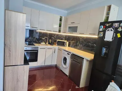 a kitchen with white cabinets and a washer at Апартамент на център Приморско in Primorsko