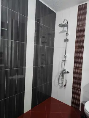 a shower in a bathroom with black and white tiles at Апартамент на център Приморско in Primorsko