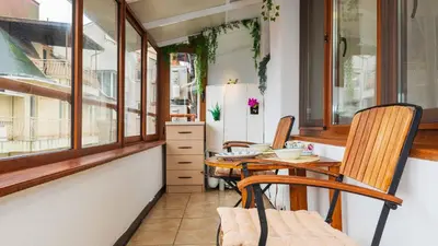 a dining room with a table and chairs and windows at Апартамент Уютна почивка in Burgas City