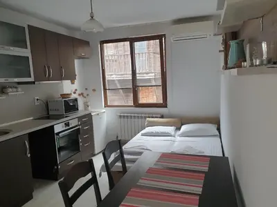 a kitchen with a table and two beds in a room at Apartament Magi in Sozopol