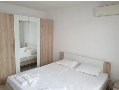 a bedroom with a white bed and a mirror at Apartament Magi in Sozopol
