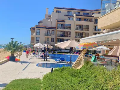 a swimming pool with umbrellas and a building at Apartments Obzor Beach C - Апартаменти Обзор Бийч С in Obzor