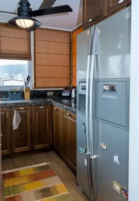 a kitchen with a stainless steel refrigerator and wooden cabinets at Modern Comfort & Vintage Charm with Panoramic View by Flat Mаnаger in Varna City