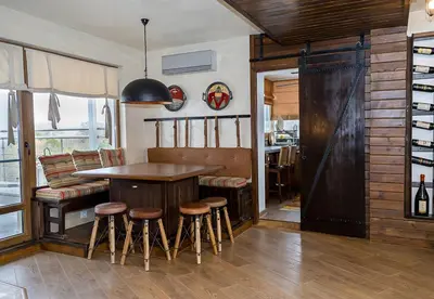 a kitchen with a wooden table and bar stools at Modern Comfort & Vintage Charm with Panoramic View by Flat Mаnаger in Varna City