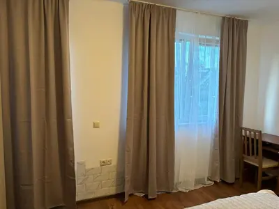 a bedroom with a window with curtains and a chair at Blue Bay Apartments in Byala