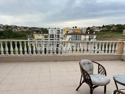 a patio with a chair and a table on a balcony at Blue Bay Apartments in Byala