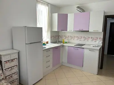 a kitchen with purple and white cabinets and a refrigerator at Апартамент в Риф 2 in Burgas City