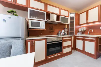 a kitchen with wooden cabinets and a microwave and a refrigerator at Downtown Аpartment with Free Parking in Varna City