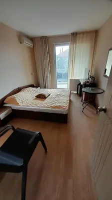 a bedroom with a bed and a table and a window at Guest House Sveti Vlas in Sveti Vlas