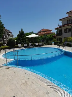 a large blue swimming pool with chairs and an umbrella at Nice 2 Bedroom Apartment with Sea and Poolview near Aheloy in Kableshkovo