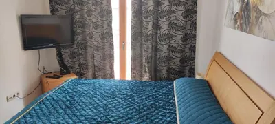 a bedroom with a blue bed and a television at Nice 2 Bedroom Apartment with Sea and Poolview near Aheloy in Kableshkovo