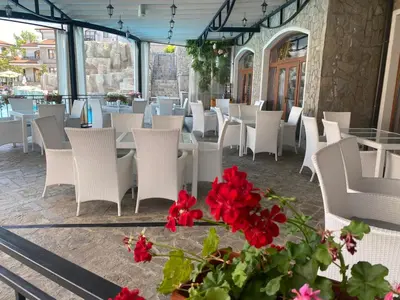 a restaurant with white chairs and red flowers at The Vineyard Spa&Resort Apartment with private garden near Aheloy in Kableshkovo