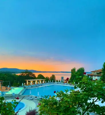 a large swimming pool with a sunset in the background at AJ Apartment 8, Santa Marina Holiday Village, Sozopol in Sozopol