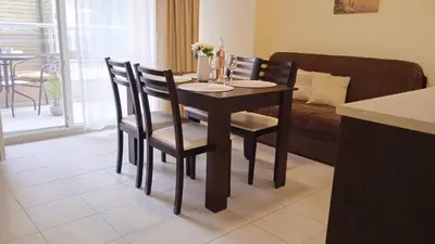 a dining room table and chairs in a room with a couch at Апартамент в непосредствена близост до плажа in Burgas City