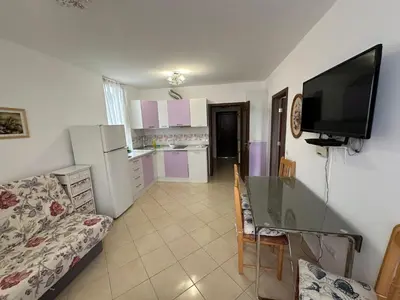 a kitchen and living room with a table and a television at Апартамент Emilia in Ravda