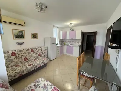 a kitchen and a living room with a couch and a table at Апартамент Emilia in Ravda