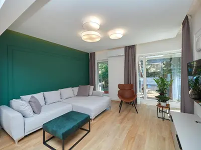 a living room with a white couch and a green wall at n17 Garden - Parking - WorkDesk - Blackout Rolls- Netflix - Wash&Dry in Burgas City