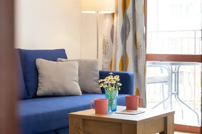 a blue couch with a vase of flowers on a table at Lidia Odrin by RV Apartments in Varna City