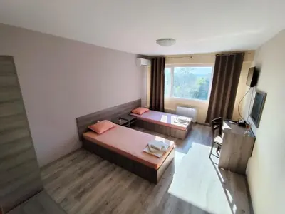 a hotel room with two beds and a television at Хостел Спортна база Ветрен in Burgas City