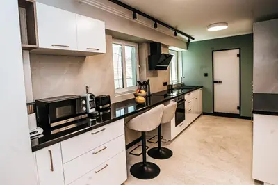 a kitchen with white cabinets and a black counter top at The Loft - Parking - Washer&Dryer - Port view - Balcony in Burgas City