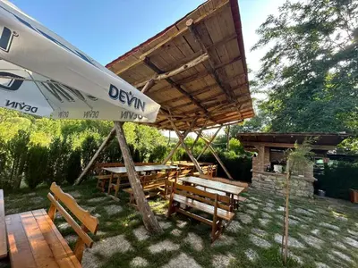 a patio with an umbrella and a table and chairs at Вилно селище Зора in Shkorpilovtsi