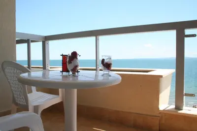 a table on a balcony with a view of the ocean at Apartments Helios in Pomorie