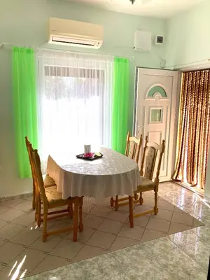 a dining room with a table with chairs and green curtains at Gemütliche Ferienwohnung zwischen Bergen und Meer in Orizare