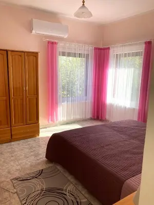 a bedroom with a bed and a window with pink curtains at Gemütliche Ferienwohnung zwischen Bergen und Meer in Orizare