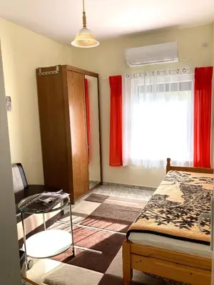 a bedroom with a bed and a window with red curtains at Gemütliche Ferienwohnung zwischen Bergen und Meer in Orizare