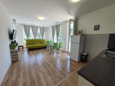 a living room with a yellow couch and a kitchen at Neptun-Blue in Primorsko