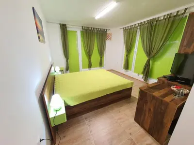 a green bedroom with a bed and a tv at Neptun-Green in Primorsko
