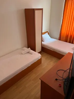 a room with two beds and a tv in it at Хотел Стоянови in Ravda