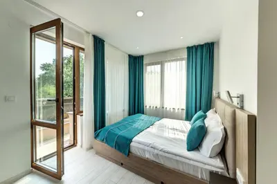 a bedroom with a bed and a large window at Апартаменти с чадъри и шезлонги на плажа - Свети Никола Каваците in Sozopol