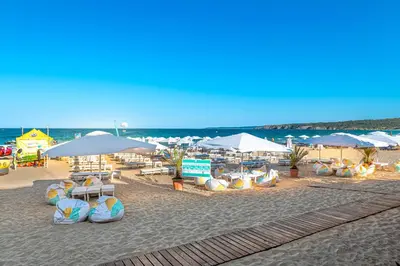 a beach with chairs and umbrellas and the ocean at Апартаменти с чадъри и шезлонги на плажа - Свети Никола Каваците in Sozopol