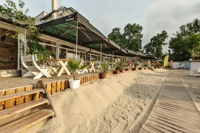 a restaurant with benches and plants in front of it at Апартаменти с чадъри и шезлонги на плажа - Свети Никола Каваците in Sozopol