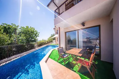 a swimming pool with a table and chairs next to a house at Villa Belissima in Sveti Vlas