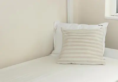 a white bed with a striped pillow on it at Cozy & Functional by the Opera in Varna City