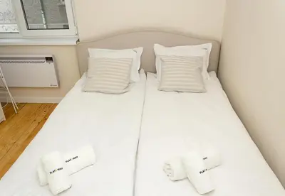 a bed with white sheets and pillows in a room at Cozy & Functional by the Opera in Varna City