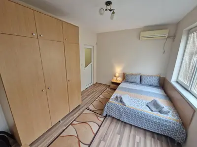 a bedroom with a bed and cabinets and a window at Lazur Sea Garden 2 in Burgas City