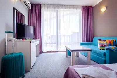 a living room with a blue couch and a television at Hotel Oasis Del Mare in Lozenets