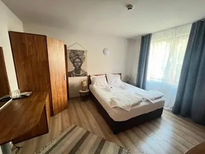 a bedroom with a bed and a wooden floor at Къща за гости Беглик таш 3 in Primorsko