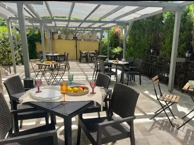 a patio with tables and chairs and a pergola at Къща за гости Беглик таш 3 in Primorsko