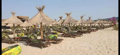 a group of chairs and umbrellas on a beach at Къща за гости Беглик таш 3 in Primorsko