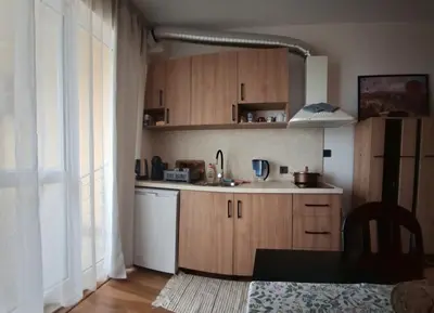 a kitchen with wooden cabinets and a white dishwasher at Студио Бяла in Byala