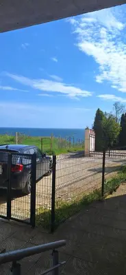 a fence with a car parked next to the ocean at Студио Бяла in Byala