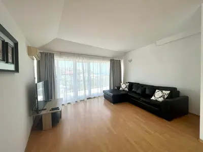 a living room with a black couch and a television at Апартамент Съни Хаус - Sunny House Apartment in Byala