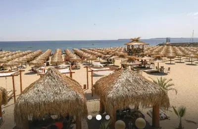 a beach with many straw umbrellas and the ocean at Sea Side Apartment with Balcony in Sveti Vlas
