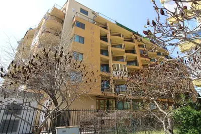 a yellow building with a tree in front of it at Amadeus 5 - Menada Apartments in Sunny Beach
