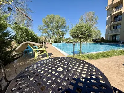a table and chair next to a swimming pool at Menada Aphrodite Green Apartments in Sunny Beach